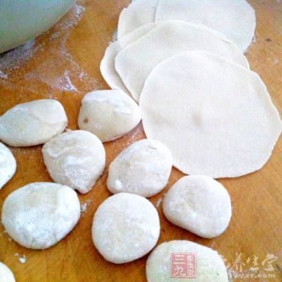 一手拿捍面棍,一手拿小圓餅狀的面糰 一手拿捍面棍,一手拿小圓餅狀的面糰