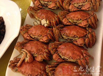 把螃蟹背朝下鋪在盤子裡，把鹽、味精、姜末均勻的撒在螃蟹上面