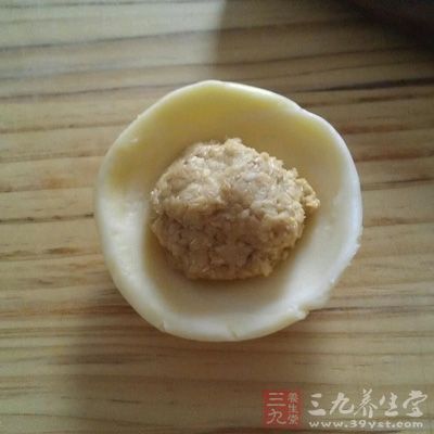 取一個餅皮，按壓成圓餅，將五仁餡放在上面