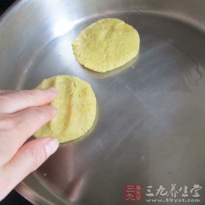將適量玉米面團平按壓放入鍋裡