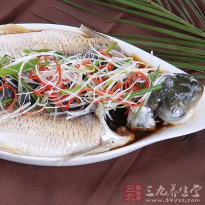 蒸熟的魚從鍋中取出，倒掉裡面的汁，撒上青紅椒絲和蔥絲