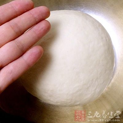 取出饧發好的面團,面板上撒些干面粉,用力將面團揉至表面光滑 取出饧發好的面團,面板上撒些干面粉,用力將面團揉至表面光滑